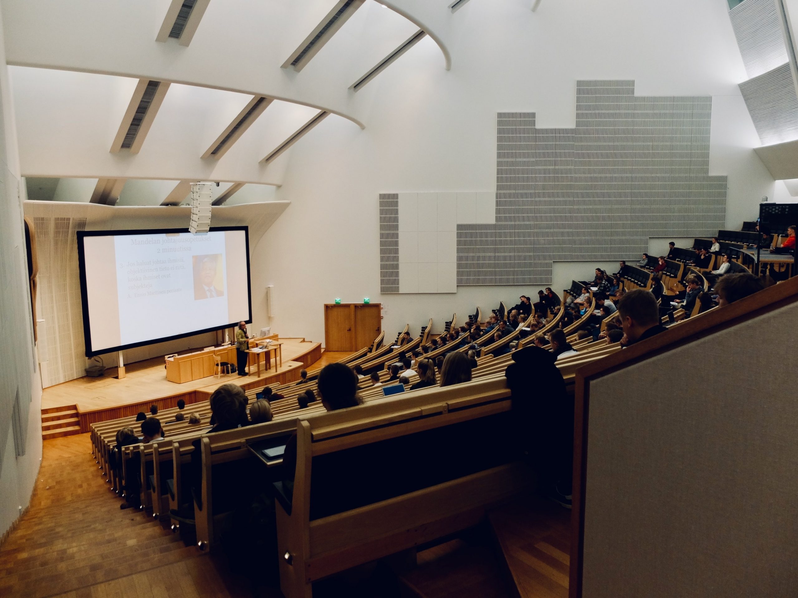 A lecture hall at the University of Virginia, featuring a large screen and an audience of people.