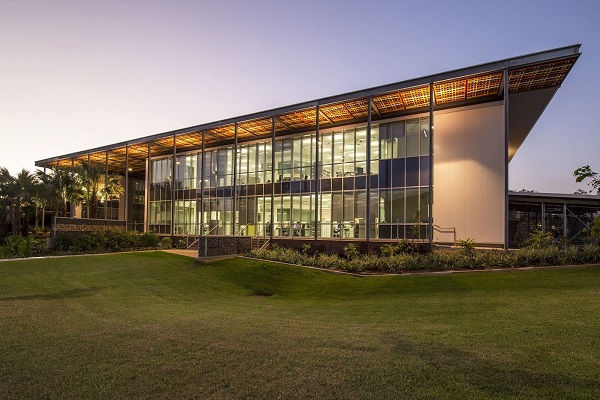 A glass building with a lush green lawn, representing Charles Darwin University.